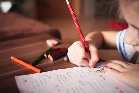 Schule: Kind schreibt mit Stiften