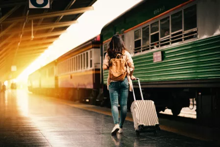 Frau mit Koffer am Bahnsteig