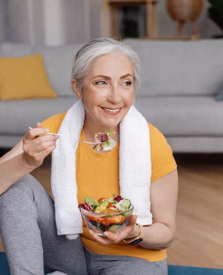 Ältere sportliche Frau isst Salat