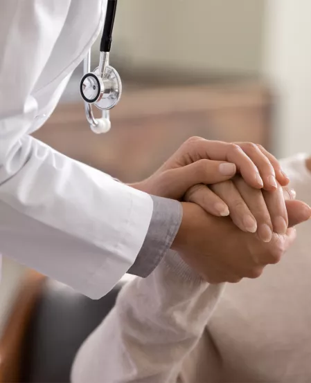 Arzt hält einer Frau die Hand, Zuversicht und Hoffnung