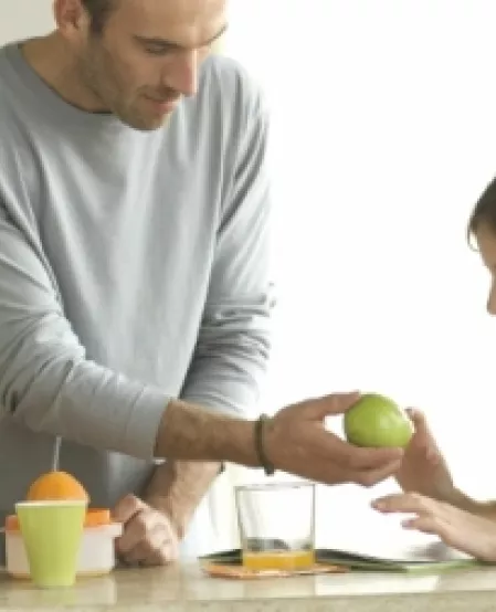 Mann gibt Kind einen Apfel