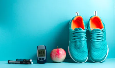 Laufschuhe, Apfel, Messgerät und Pen liegen vor türkisem Hintergrund