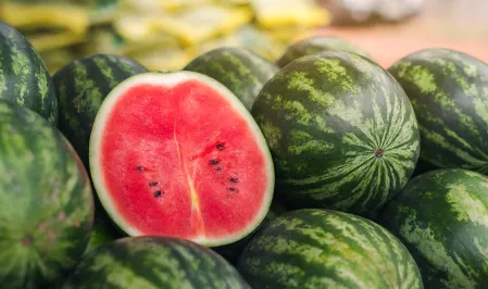 Viele Wassermelonen, eine ist halbiert. 