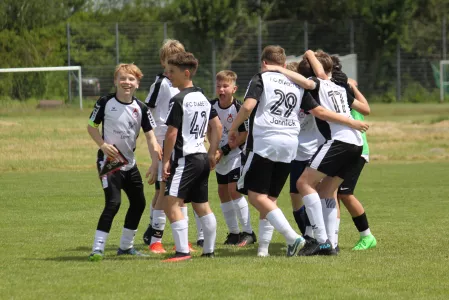 Das Fußballteam FC Diabetes feiert auf dem Fußballplatz. Sie tragen schwarz-weiße Trikots