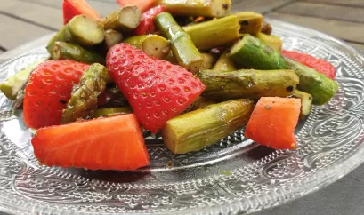 grüner Spargel und Erdbeeren als Salat auf einer Glasplatte angerichtet