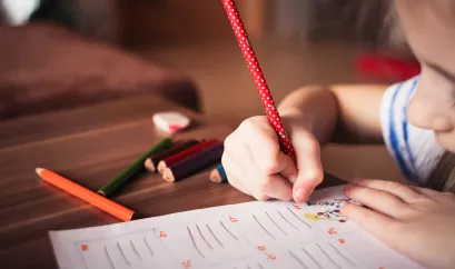Schule: Kind schreibt mit Stiften