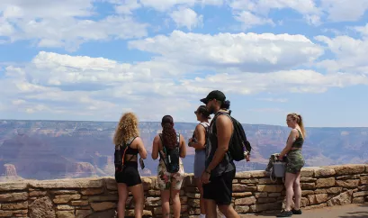 eine Gruppe junger Menschen steht vor dem Grand Canyon. Eine Frau trägt einen CGM-Sensor