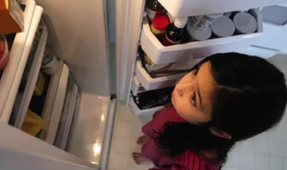 Kind schaut in Kühlschrank